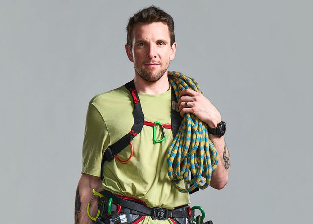 Brent Hocking in a climbing harness with a coiled rope over his shoulder